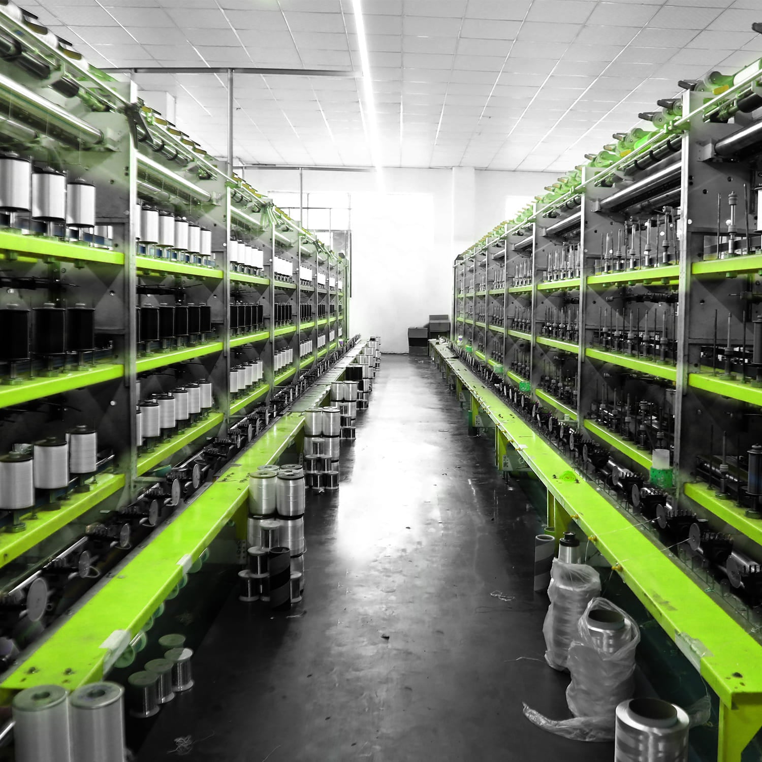 Industrial textile factory with green machinery and spools of thread in production line
