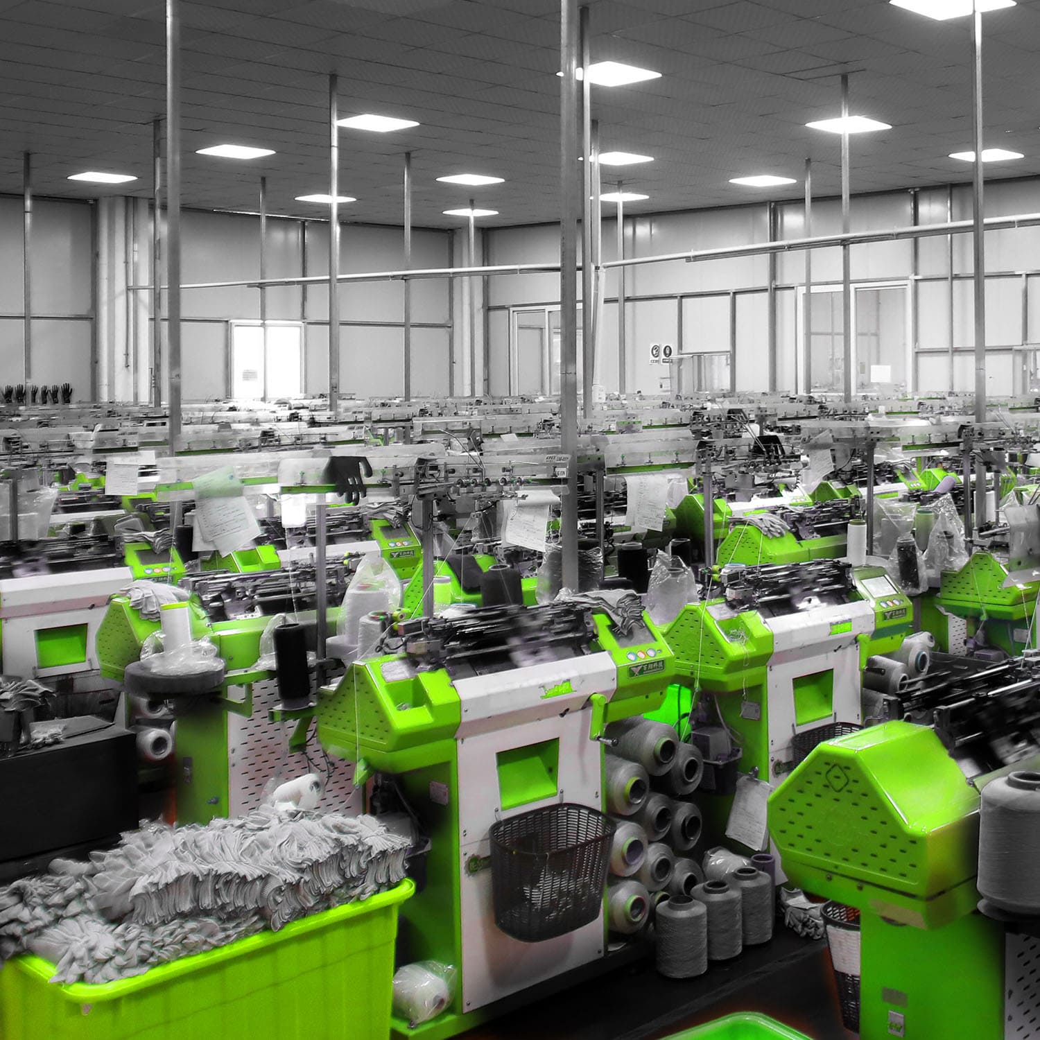 Industrial knitting machines producing safety gloves in a factory setting
